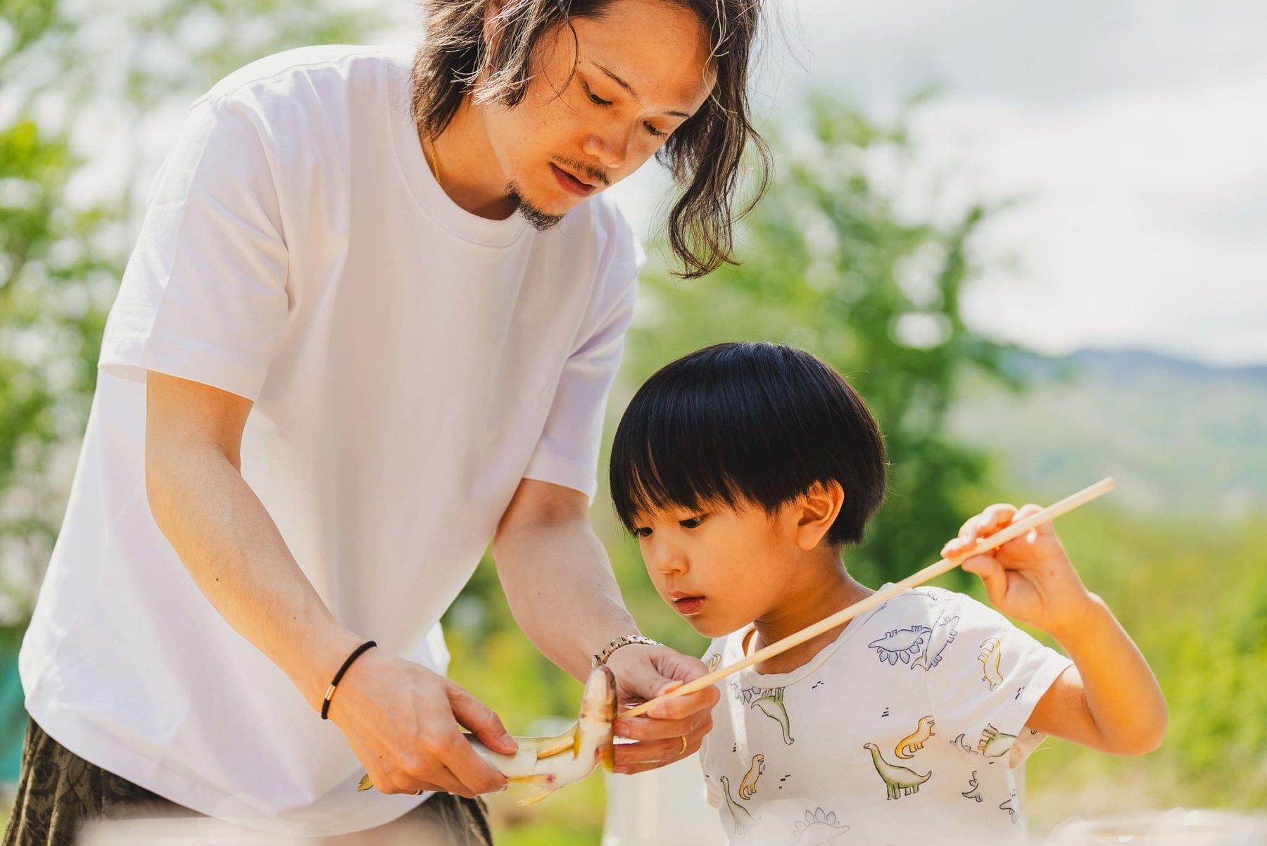 焼きたての鮎を頬張る父と息子